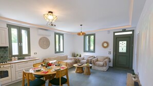 A spacious kitchen with a dining area, a sofa set, and a small table with a plant. - Unity Villa
 (KEFALONIA)
