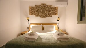 A neatly made bed with white linens and two folded towels, a wooden headboard, and a decorative wall hanging above. - Unity Villa
 (KEFALONIA)
