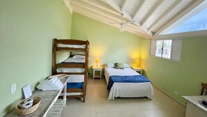 Una habitación pequeña y acogedora con una cama litera, una cama individual, un escritorio con lámpara y una ventana con persianas.