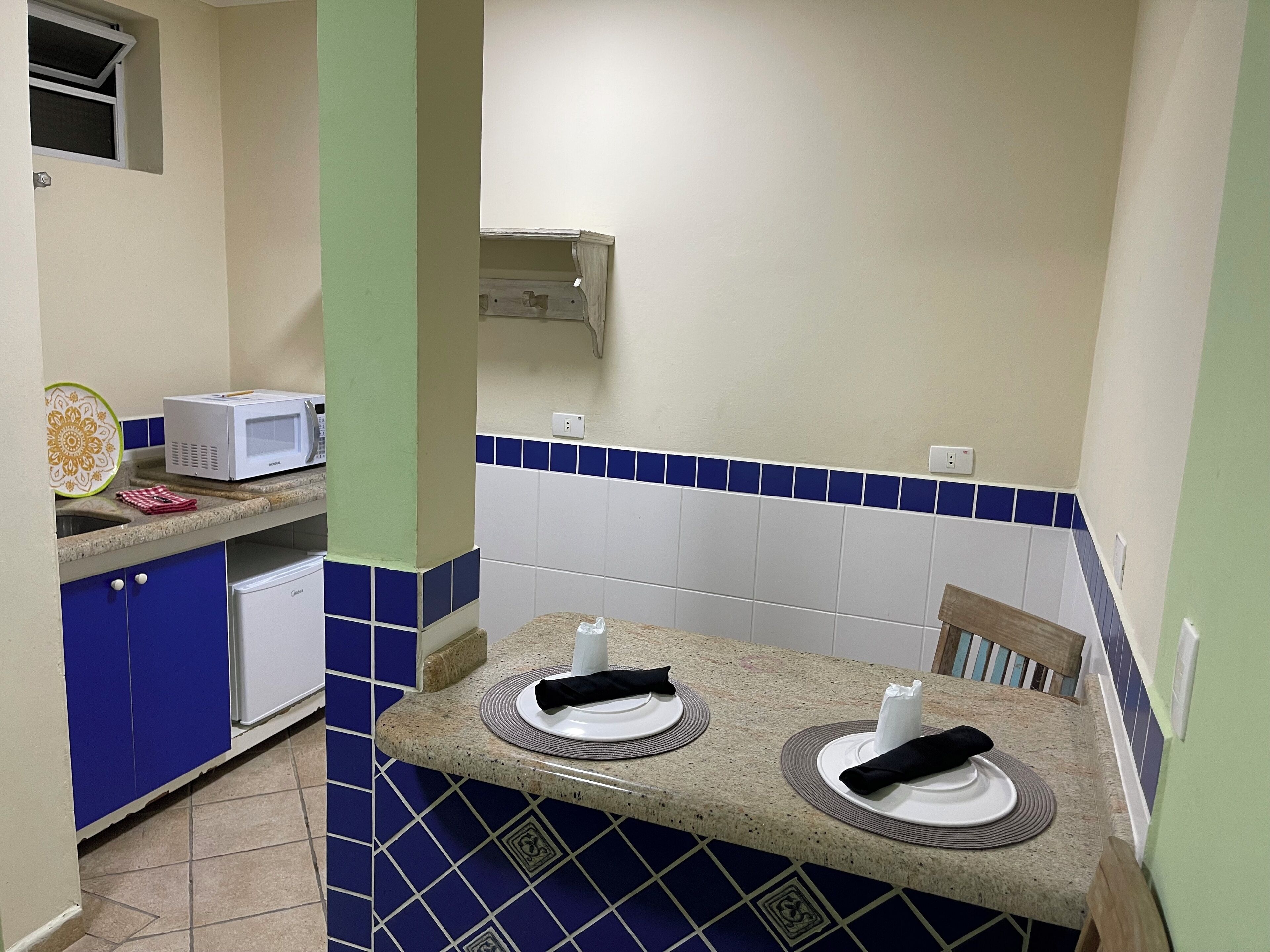 A small kitchen with a microwave, a sink, and a dining area with two chairs and a table.