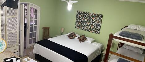 A room with a bed, a desk with a chair, a wardrobe, a ceiling fan, and a wall-mounted artwork.