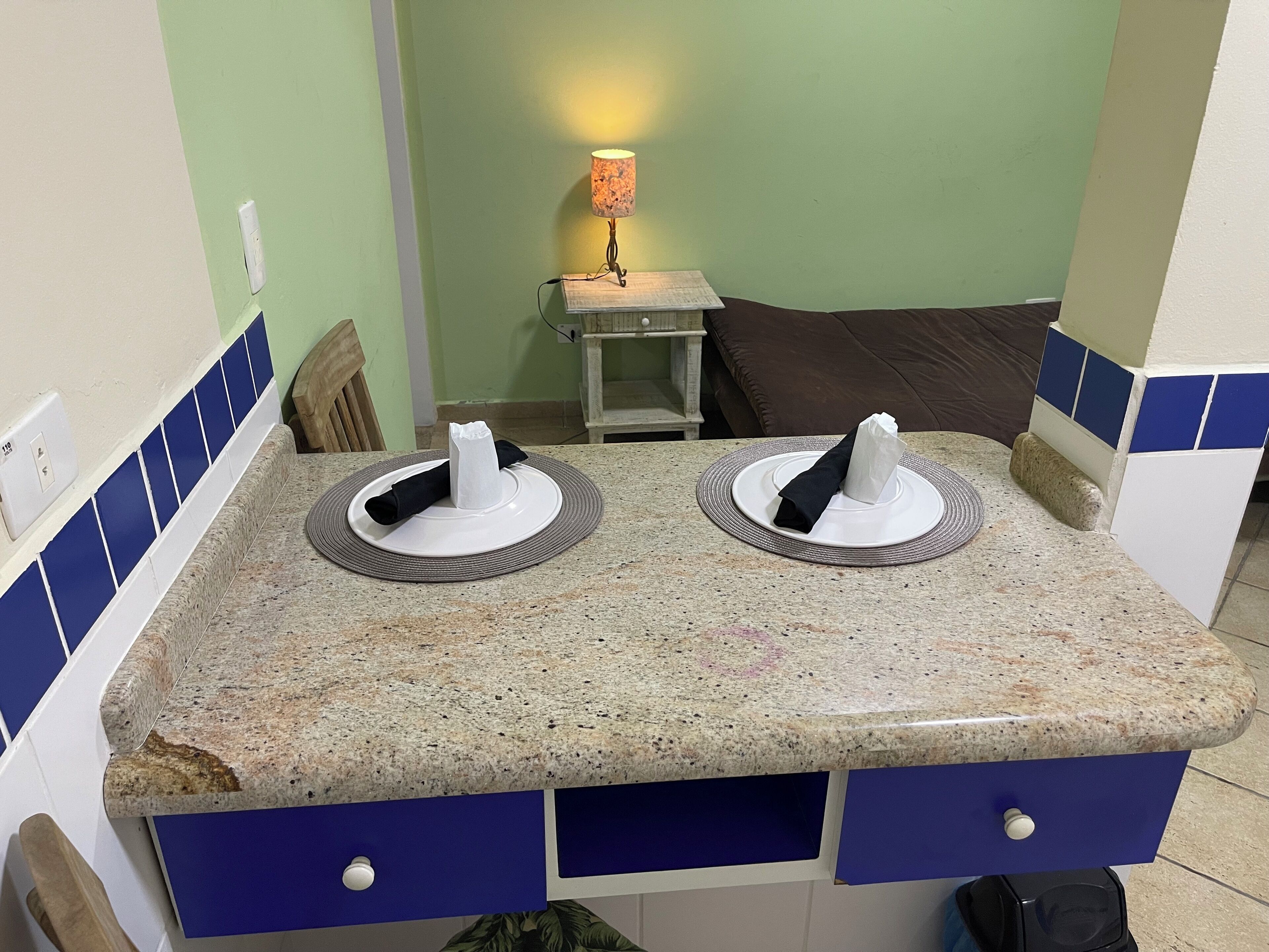 A bathroom with two sinks, a towel rack, and a small table with a lamp.