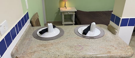 A bathroom with two sinks, a towel rack, and a small table with a lamp.