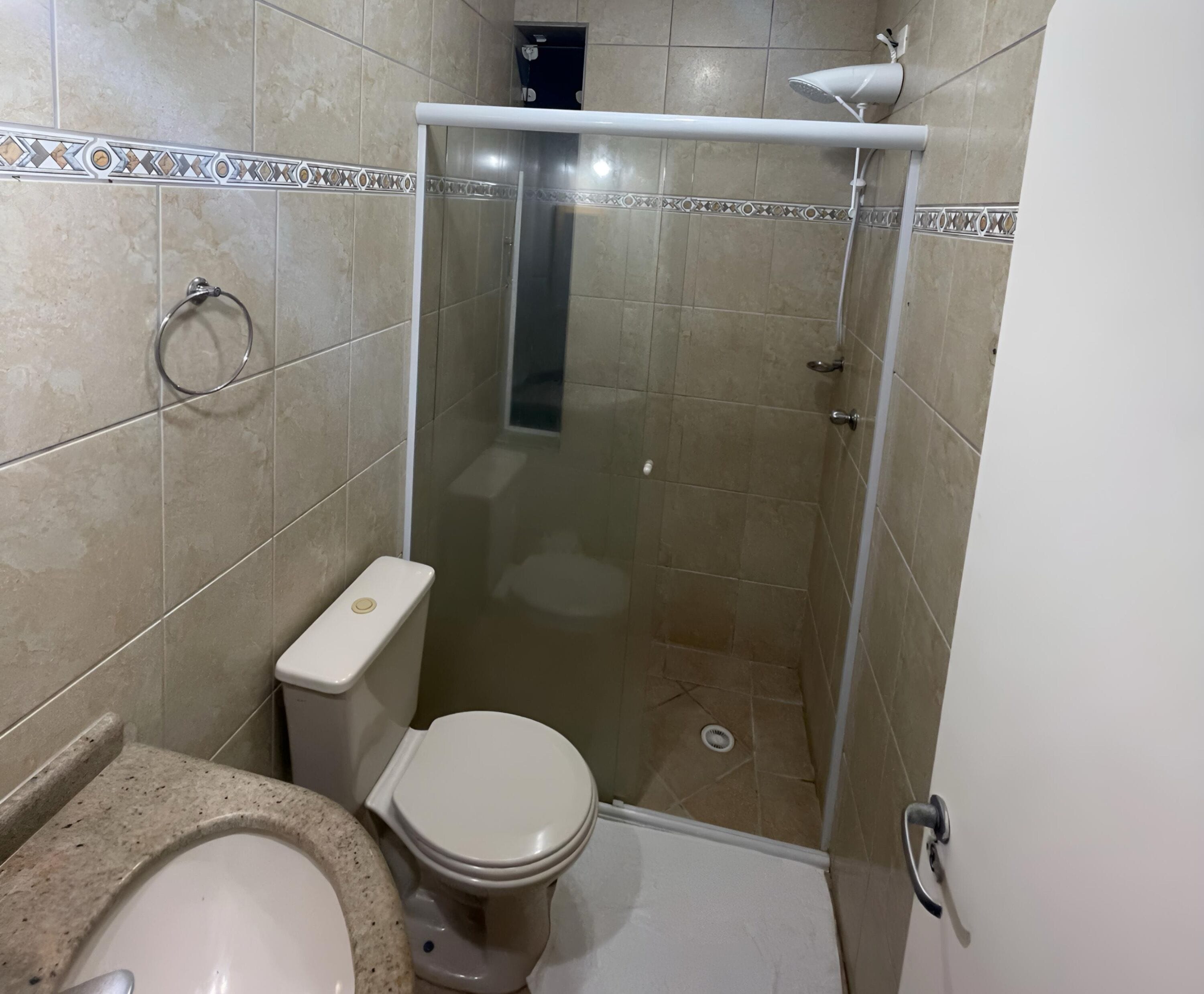 Uma casa de banho com sanita, cabine de duche e lavatório.
