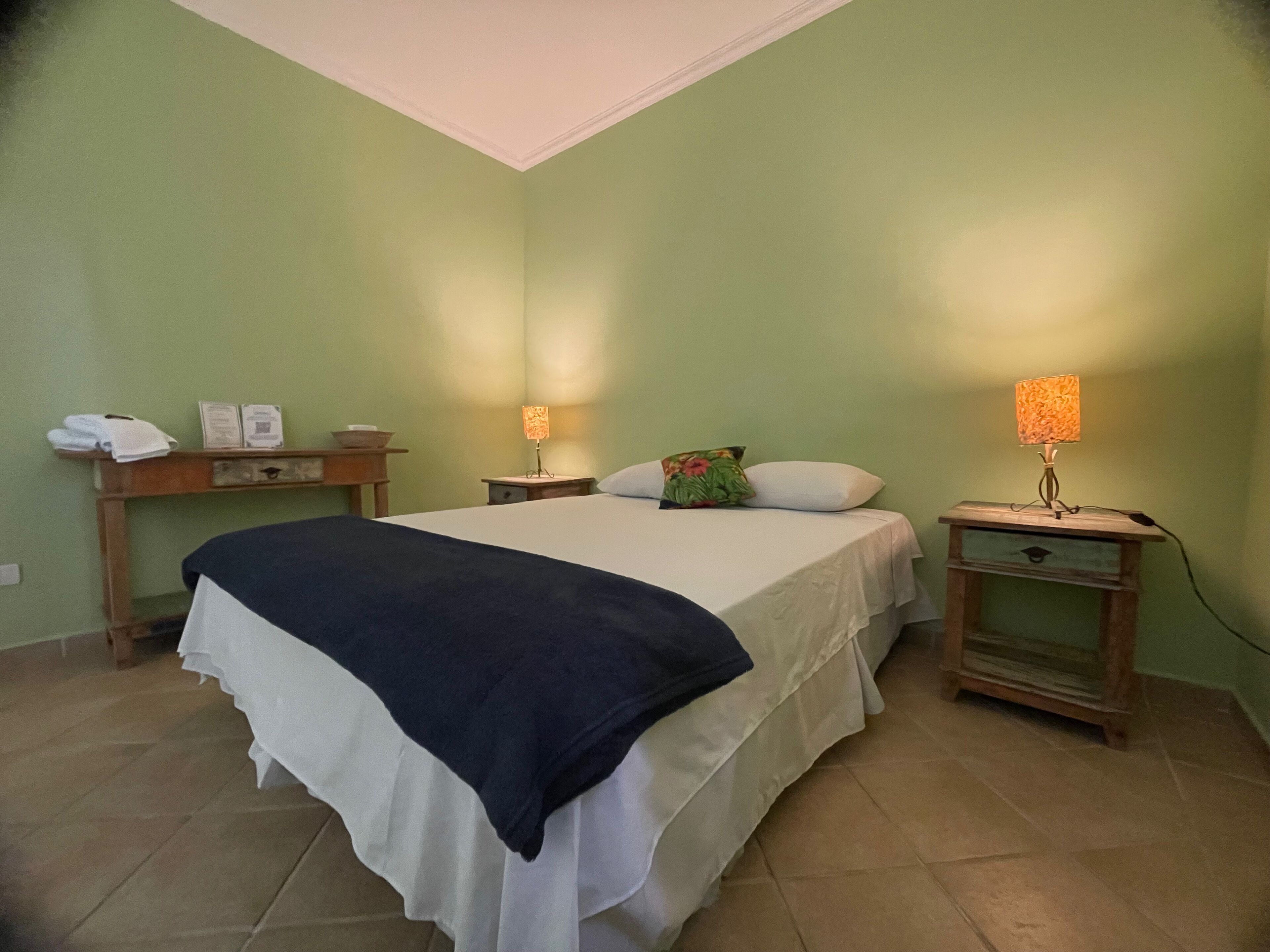 A bedroom with a bed, two bedside tables, a nightstand, a lamp, and a small cabinet.