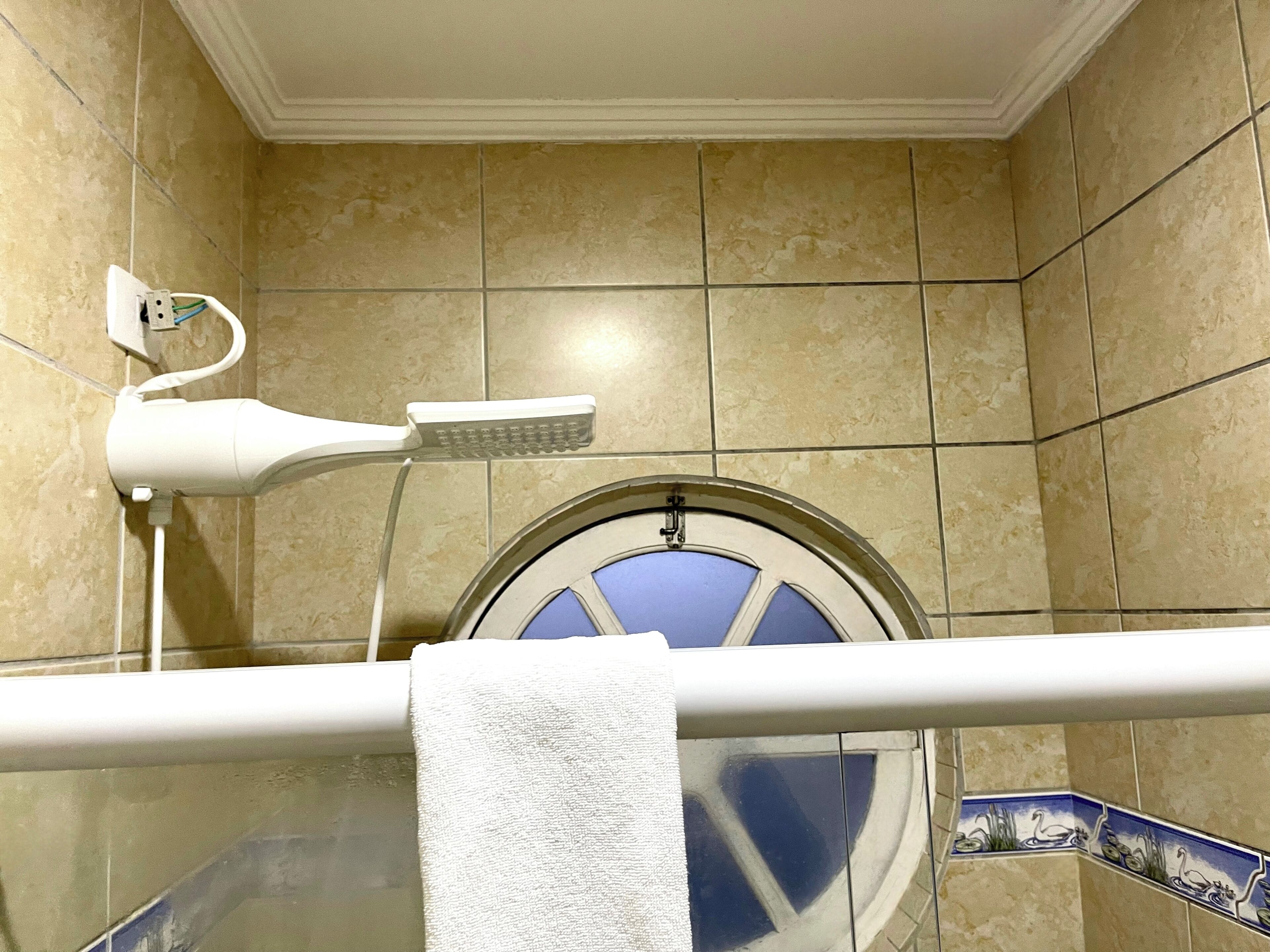 A bathroom with a shower, a towel rack, and a wall-mounted hairdryer.