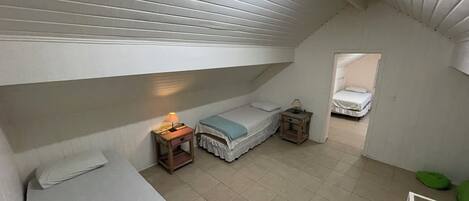 A dorm-style room with bunk beds, a small bedside table with a lamp, and a window.