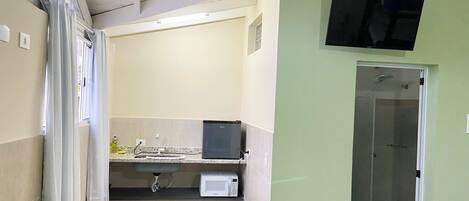 A compact bathroom with a sink, mirror, and a television mounted on the wall.