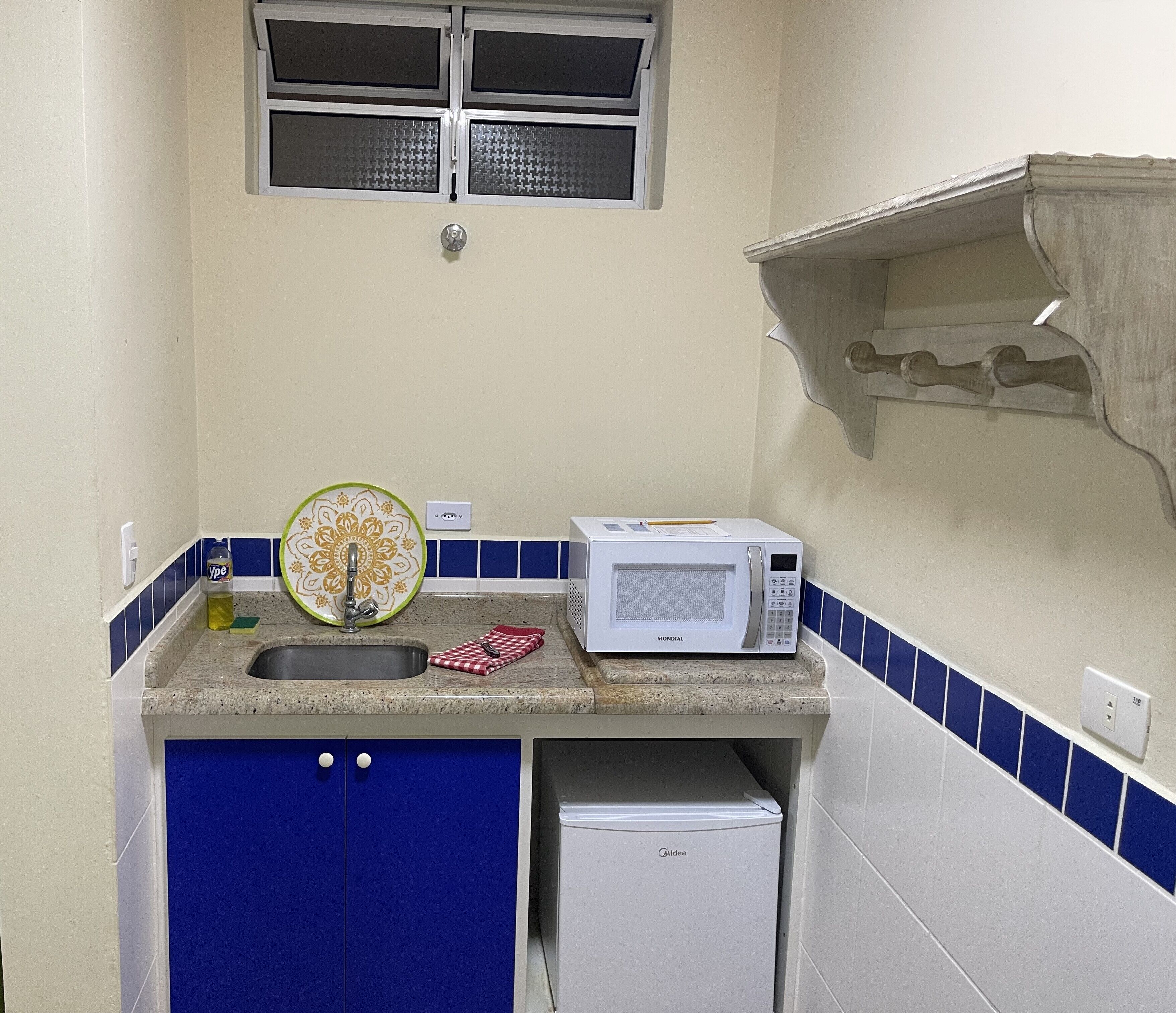 A compact kitchen with a sink, a microwave, and a small refrigerator.