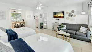 A hotel room with two beds, a sofa, a small table, a TV, and a ceiling fan. - Hollywood Beach Escapade Studio w/ Free Parking (Hollywood)