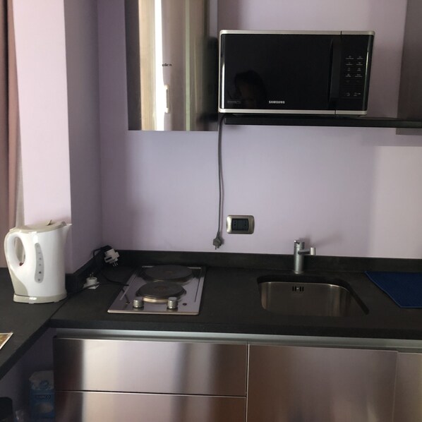 A kitchen with a microwave, kettle, and gas stove. - Attico Coloseo with rooftop (Roma)