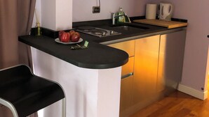 A compact kitchen with a microwave, a sink, and a bar area with stools. - Attico Coloseo with rooftop (Roma)