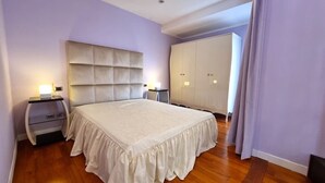 A bedroom with a large bed, a nightstand, a wardrobe, and a headboard. - Attico Coloseo with rooftop (Roma)