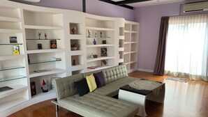 A modern living room with a sectional sofa, white shelving units, and a wooden floor. - Attico Coloseo with rooftop (Roma)