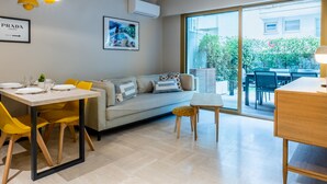 A modern living room with a dining area, a sofa, a coffee table, and a view of the outdoors. - Downtown Cannes, Apartment with Garden (Cannes)