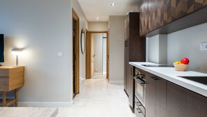 A modern kitchen with a white countertop, wooden cabinets, and a fruit bowl on the counter. - Downtown Cannes, Apartment with Garden (Cannes)