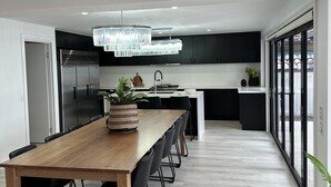 Une cuisine moderne avec une longue table en bois, des chaises noires et un lustre.