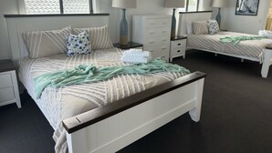 Une chambre avec deux lits, une table de chevet, une commode et une fenêtre donnant sur le toit.