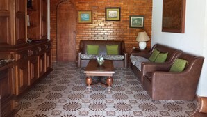A living room with a brick wall, wooden furniture, and patterned floor tiles.