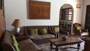 A living room with a brown sofa set, a wooden coffee table, and patterned floor tiles.