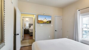 A hotel room with a bed, a painting of a cathedral, a door, and a window. - Spacious Urban Living Near French Quarter (New Orleans)
