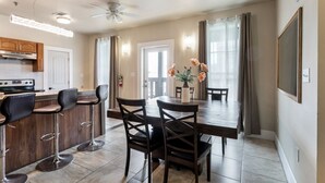 A modern kitchen with a central island, bar stools, and a dining table with chairs. - Spacious Urban Living Near French Quarter (New Orleans)