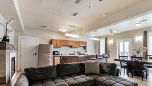 A modern kitchen with wooden cabinets, a refrigerator, and a microwave. There is a dining area with a table and chairs. - Spacious Urban Living Near French Quarter (New Orleans)