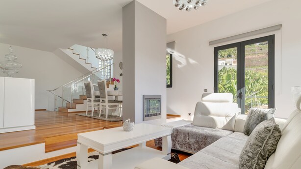 A modern living room with a white sofa, a coffee table, and a staircase leading to an upper level. - Countryside Charm  (Camara de Lobos)