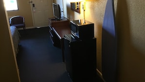 Een hotelkamer met een bureau, een televisie, een lamp en een bed.