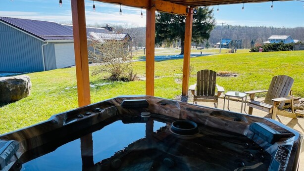 Ein Whirlpool unter einer Holz-Pergola mit Blick auf einen Rasen und ein Haus im Hintergrund.