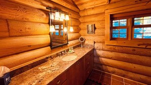 Ein Badezimmer einer Holzhütte mit Waschbecken, Spiegel und Fenster.
