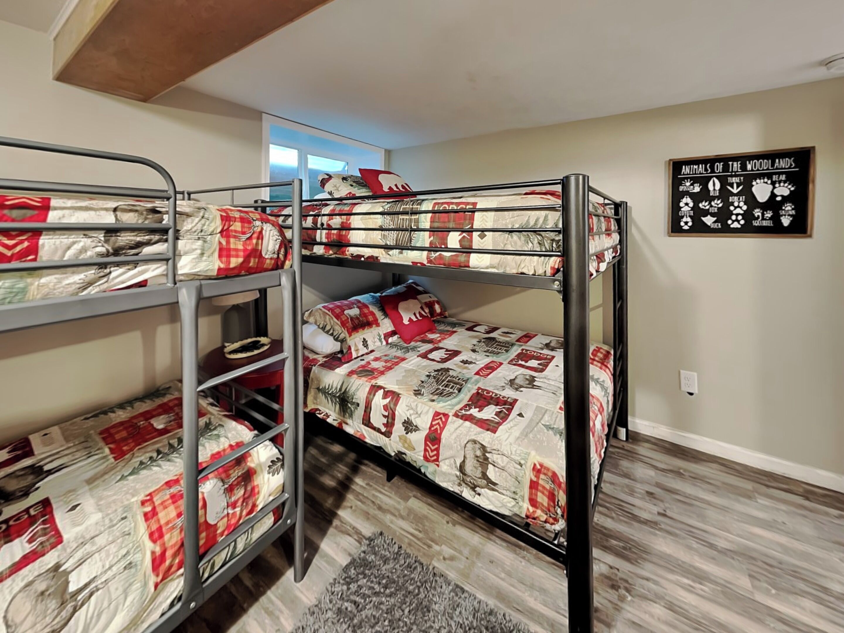 Une chambre avec un lit superposé, une fenêtre, un tapis et un panneau décoratif sur le mur.
