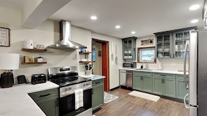 A modern kitchen with a stove, oven, microwave, and refrigerator. - The Whiskey Barrel Lodge by Taylor Made Deep Creek (Oakland)