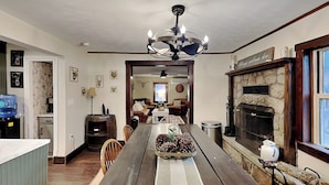 A dining area with a long wooden table, a stone fireplace, and a chandelier. - The Whiskey Barrel Lodge by Taylor Made Deep Creek (Oakland)