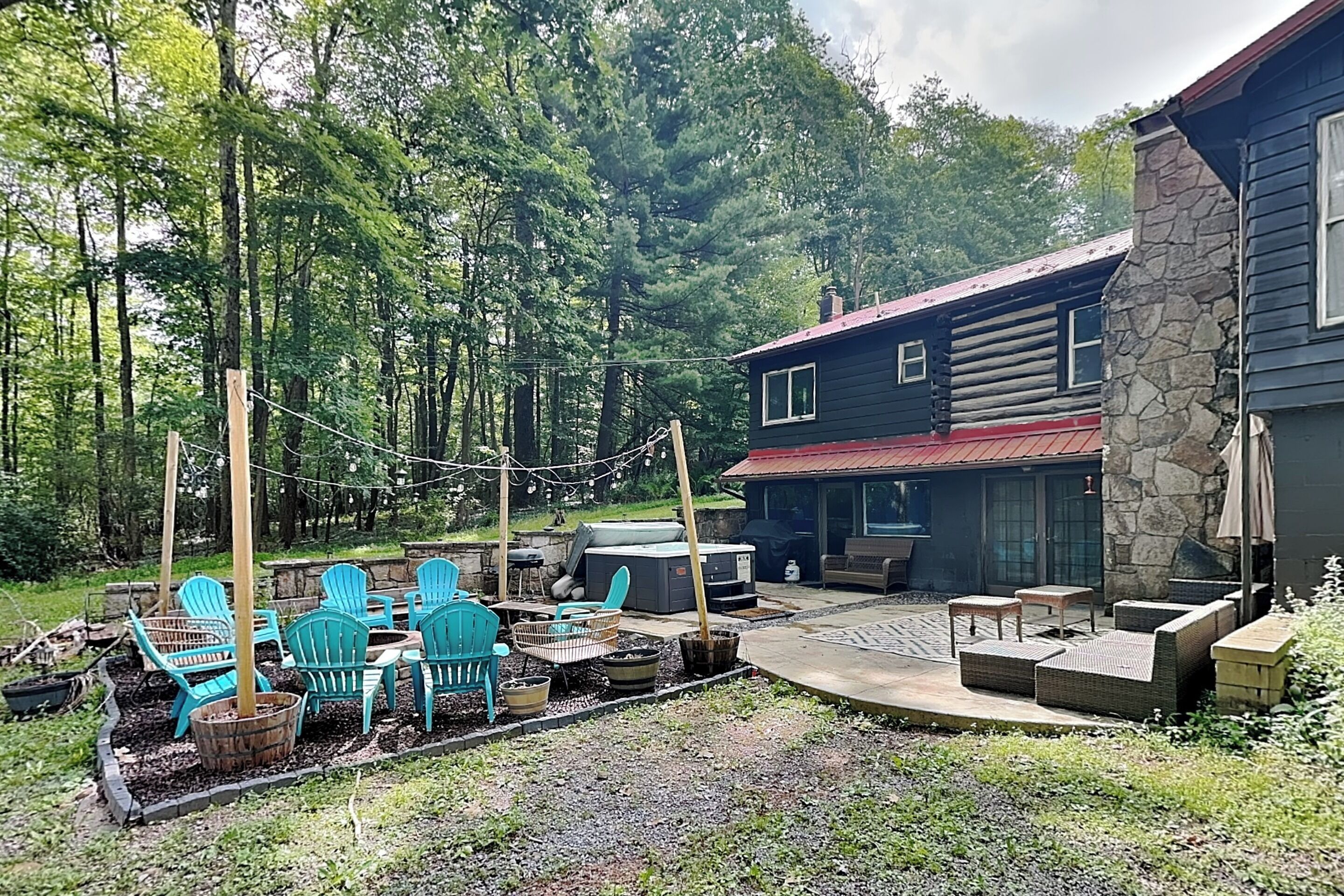 A rustic cabin with a stone exterior, a patio area with outdoor furniture, and a forested backdrop.