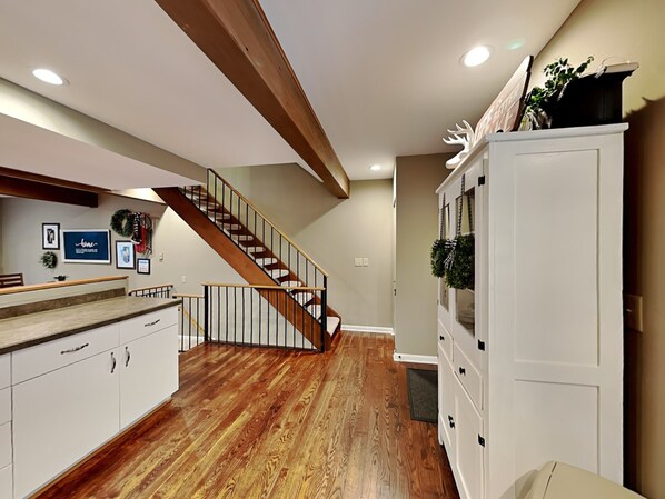 A modern kitchen with wooden flooring, a built-in counter, and a staircase leading to another level. - Villages of Wisp 66 Bright Passage by Taylor Made Deep Creek (McHenry)