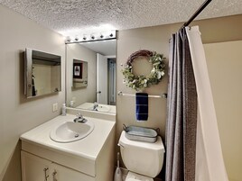 Un baño con lavamanos, espejo, inodoro y cortina de ducha.