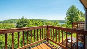 Une terrasse en bois offrant une vue sur un lac et des collines boisées.