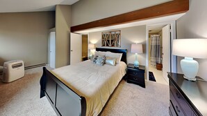Une chambre à coucher comprenant un lit, des tables de chevet, une armoire et une poutre au plafond.