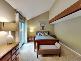Un dormitorio con cama, mesitas de noche, lámpara, un banco y una obra de arte con cabeza de ciervo.