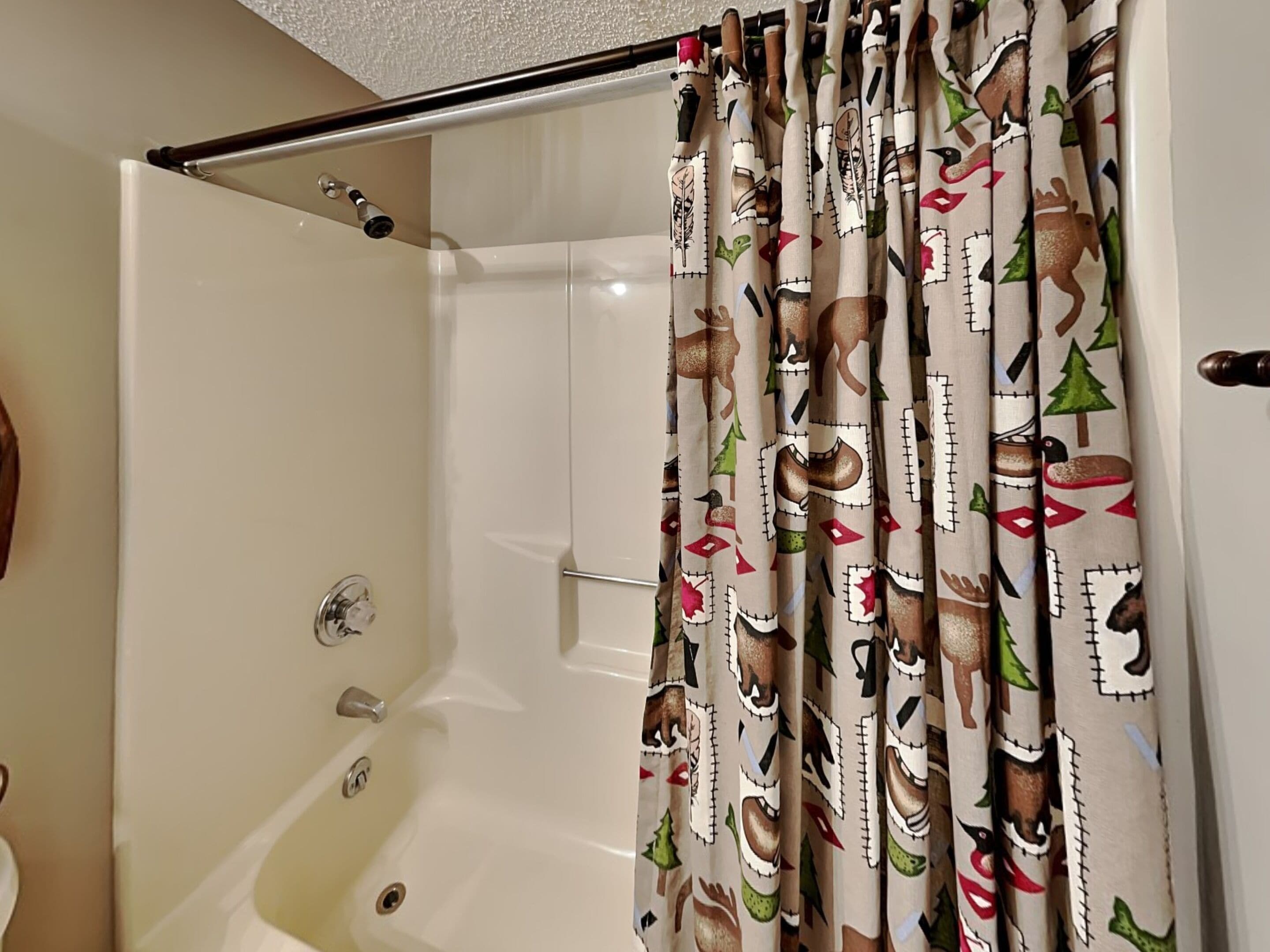 Un bagno con una vasca, un box doccia con un motivo festivo e un portascopevoli.
