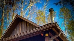 Eine rustikale Holzhütte mit Holzwänden, einem Schornstein und einer Veranda mit einer Bank.
