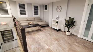 A modern living room with a beige sofa, a coffee table, a potted plant, and a white cabinet.