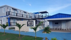 A modern multi-story building with balconies, a covered outdoor seating area, and a pool.