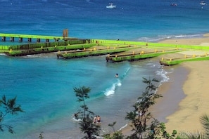 Une zone côtière avec une plage, une jetée et des bateaux sur l’eau.