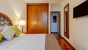 A hotel room with a bed, bedside table, lamp, and a wooden wardrobe. - Stylish & Charming in Consolação/Higienópolis • Parking • 3rd Guest Free (Sao Paulo)