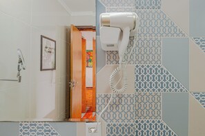 A bathroom with a hairdryer mounted on the wall, a framed picture on the wall, and a door leading to another room. - Stylish & Charming in Consolação/Higienópolis • Parking • 3rd Guest Free (Sao Paulo)
