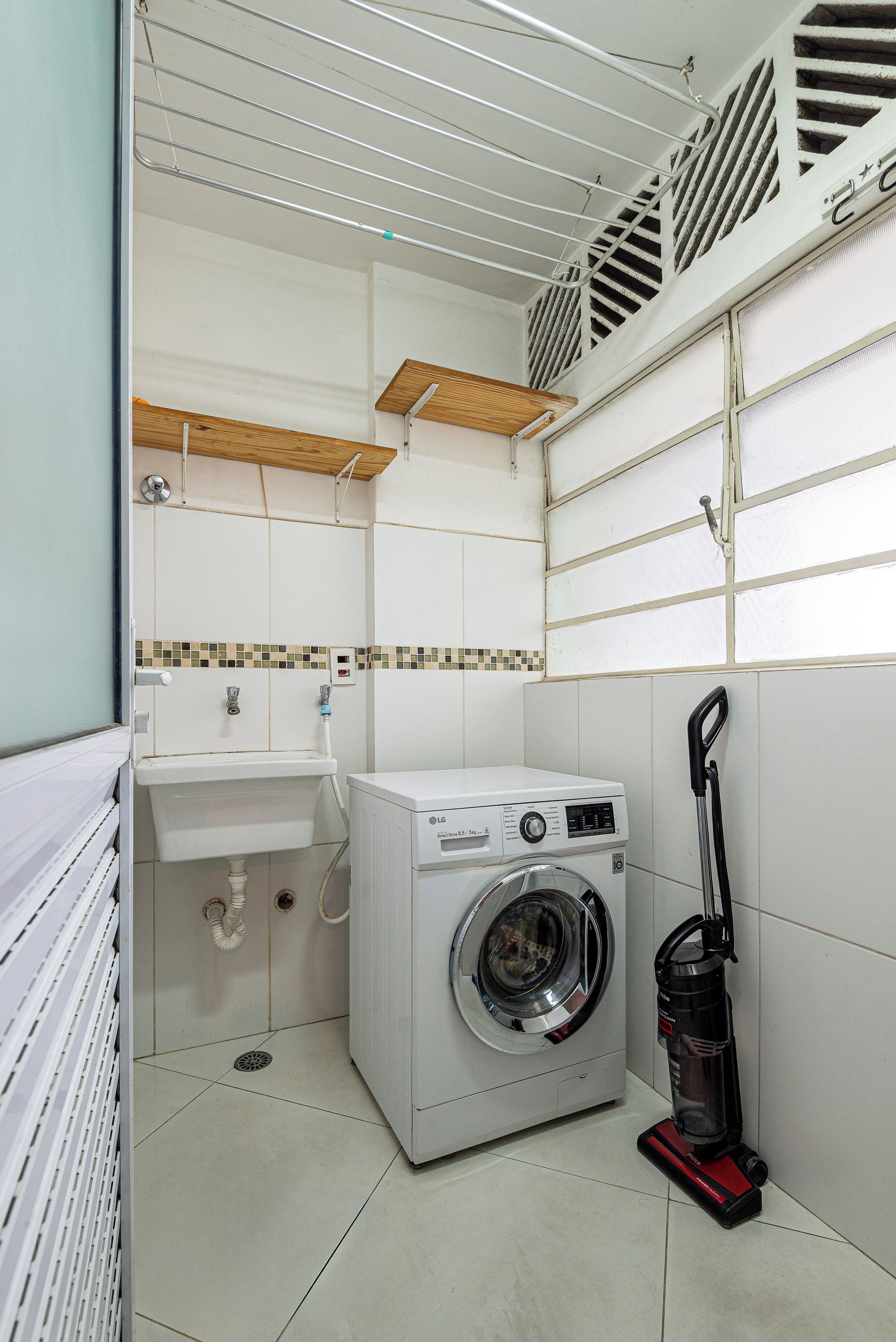 A compact laundry room with a washing machine, a sink, and a mop.