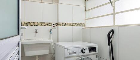 A compact laundry room with a washing machine, a sink, and a mop.