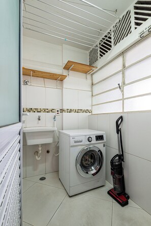 A compact laundry room with a washing machine, a sink, and a mop. - Stylish & Charming in Consolação/Higienópolis • Parking • 3rd Guest Free (Sao Paulo)